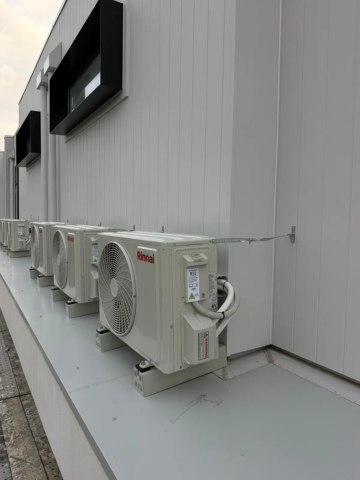 A row of wall-mounted multi-split condensers on cantilever brackets along an exterior service wall in Richmond